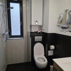 a small bathroom with a toilet with a window at Olive Ultracentral Craiova in Craiova
