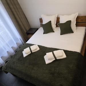 a bedroom with two beds with white sheets and green pillows at Olive Ultracentral Craiova in Craiova