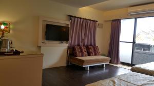 a room with a chair and a tv and a window at Qinbian B&B in Jiufen
