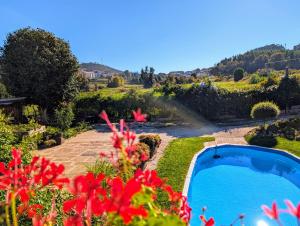 a garden with a swimming pool and red flowers at 3HOUSE Sol na Eira em Paredes in Rebordosa