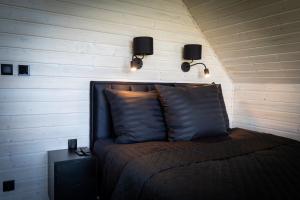 a bedroom with a bed with two lights on the wall at Black barn in Rusinowo