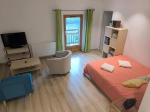 a bedroom with a bed and a chair and a television at Studio rénové avec balcon & vue sur les montagnes in Saint-Clément sur Durance