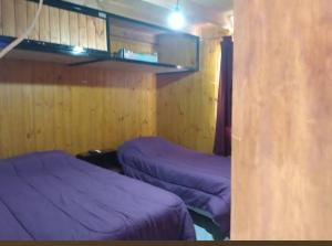 two beds in a room with purple sheets at Cabaña San Francisco in Cholila