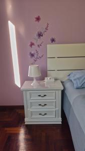 ein weißer Nachttisch mit einer Lampe darauf neben einem Bett in der Unterkunft Casa Kendra in Montegrotto Terme