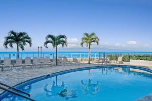 a swimming pool with palm trees and the ocean at Hololani B204 · HL B204 Beachy Chic Updated OceanFront 2BD in Kahana