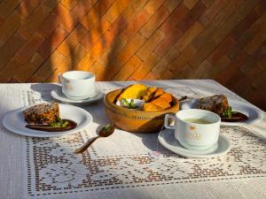 a table with two cups of tea and a bowl of bread at Pousada Unaí in Porto De Galinhas