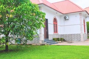 una casa bianca con tetto rosso e cortile verde di 1 Bedroom Bungalow in Alalubosa GRA a Ibadan