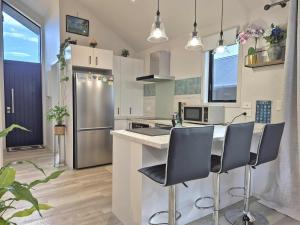 a kitchen with a counter with chairs and a refrigerator at Amie's Charming Villa in Tauranga