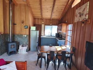 a kitchen with a table and chairs and a stove at Cabaña pasaje las rosas in Pucón