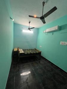 een kamer met een plafondventilator en blauwe muren bij MB Guest House in Tiruvannamalai