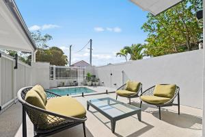 eine Terrasse mit Stühlen, einem Tisch und einem Pool in der Unterkunft Potts Villa Your Serene Beachside Escape in Pottsville