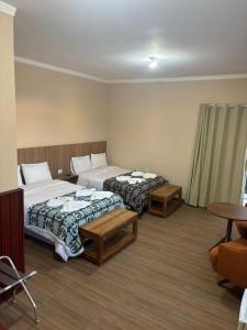 a hotel room with two beds and a table at Pousada Café em Flor -Quarto Hidromassagem in Inconfidentes +23 photos