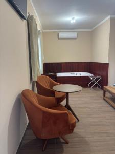 a room with two chairs and a table and a bed at Pousada Café em Flor -Quarto Hidromassagem in Inconfidentes