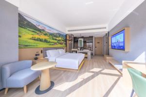 ein Hotelzimmer mit einem Bett und einem Fernseher in der Unterkunft Qiuguo Garden Hotel in Dongguan