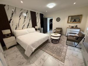 a bedroom with a white bed and a table and a chair at The Benjamin Guest House in Edenvale