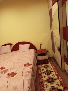 锡盖图马尔马切伊Harta in cui的一间卧室，里面有一张床和一张桌子，桌子上放着一尊红色雕像。