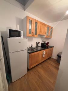 a kitchen with a white refrigerator and wooden cabinets at Logement cosy Essonne in Longjumeau