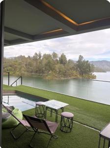 Un patio con mesa y sillas y vista al agua. en Habitación de Lujo en Guatape, en Guatapé