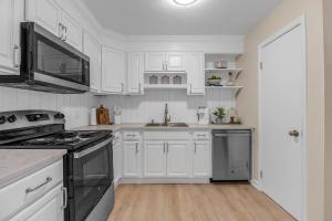 a kitchen with white cabinets and a stove top oven at Launch and Lounge Cozy Cape Canaveral Beach Townhome Near Surf and Space in Cape Canaveral