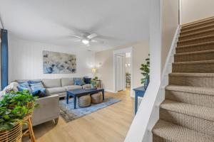 a living room with a couch and a staircase at Launch and Lounge Cozy Cape Canaveral Beach Townhome Near Surf and Space in Cape Canaveral