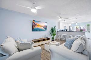a living room with two white couches and a kitchen at Stylish Townhome w Hot Tub 5 Min Walk to Beach in Cape Canaveral