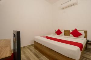 um quarto com uma cama grande com travesseiros vermelhos em Hotel O Perky Stay em Faridabad