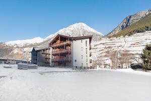 een gebouw in de sneeuw voor een berg bij Residenza Viola in Valdidentro