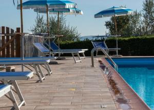a pool with chairs and umbrellas next to a swimming pool at Podere Trieste in Cialabrone +6 photos