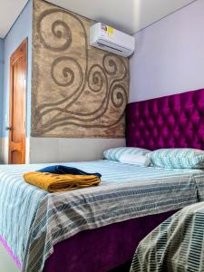 a bedroom with a bed with a purple headboard at Me Quedo Aqui, Casa Cerca del Aeropuerto de Cartagena! in Cartagena de Indias