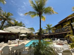 a resort with a pool and chairs and palm trees at Hotel Mar de Cabo Frio in Cabo Frio