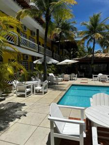 a resort with a pool and chairs and a building at Hotel Mar de Cabo Frio in Cabo Frio