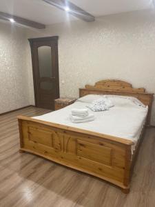a bedroom with a wooden bed with white sheets at Будинок у Олени in Pochayiv