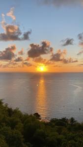 a sunset over the ocean with the sun setting at Flor de Lótus Camping in Japaratinga +5 photos