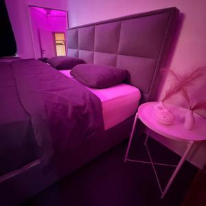 ein lila Zimmer mit einem Bett und einem Beistelltisch in der Unterkunft La Suite Liege in Seraing