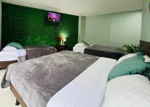 1 Schlafzimmer mit 3 Betten und einer grünen Wand in der Unterkunft Apartment 7 with Jacuzzi in the center - 3 Bedroom 2 Bath in Baños + 12 Fotos