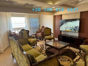 a living room with couches and chairs and a tv at شقه 103 سوبر لوكس فيو قناه السويس والبحر in Port Said