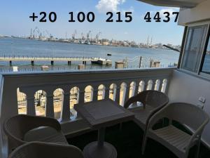 a balcony with a table and chairs and a view of the ocean at شقه 103 سوبر لوكس فيو قناه السويس والبحر in Port Said +4 photos