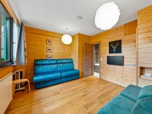 a living room with a blue couch and a tv at Beautiful studio - private garden, EV, breakfast - Chalet Hug studio in Arzier