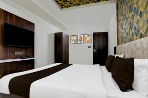 Un dormitorio con una gran cama blanca y un televisor de pantalla plana. en Super Hotel O Nana Chiloda Near Airport Formerly Green Valley, en Ahmedabad