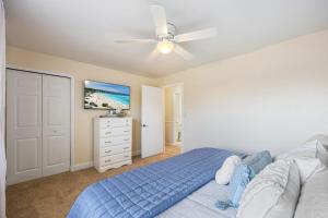 a bedroom with a blue bed and a ceiling fan at Beachside Blast Off Stylish Cape Canaveral Townhome Near Surf & Space in Cape Canaveral