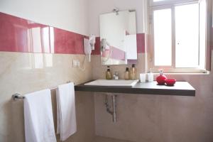 bagno con lavandino, specchio e asciugamani di B&B The Queen a Ispica