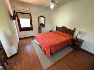 Schlafzimmer mit einem Bett mit einer roten Bettdecke und einem Spiegel in der Unterkunft NOVA Hotel Pinamar in Pinamar