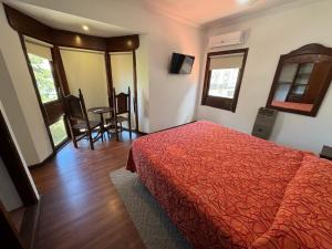 1 dormitorio con cama roja, mesa y sillas en NOVA Hotel Pinamar, en Pinamar