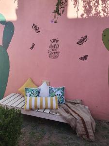 een bank tegen een roze muur met vlinders op de muur bij Departamentos Catamarca in La Porteña