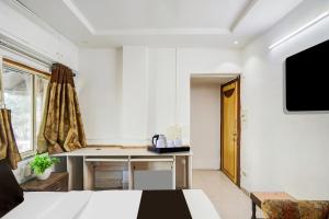 艾哈迈达巴德Super Collection O Maninagar East Formerly Maninagar Residency的白色的客房配有桌子和电视。