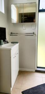 MotungararaCasa de los Tūi的带水槽和镜子的白色厨房 更多3张照片