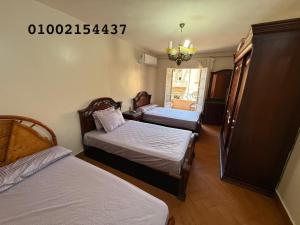 a room with three beds and a chandelier at شقه 401عائليه سوبر لوكس في وسط الحي الافرنجي في مركز المدينه in Port Said