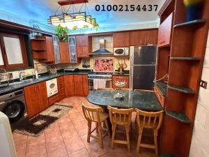 a kitchen with wooden cabinets and a table and chairs at شقه 401عائليه سوبر لوكس في وسط الحي الافرنجي في مركز المدينه in Port Said