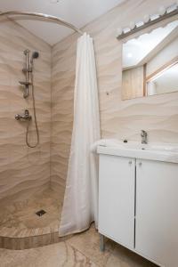La salle de bains est pourvue d'une douche et d'un lavabo blanc. dans l'établissement Scandinavian Style Apartments, à Gargždai