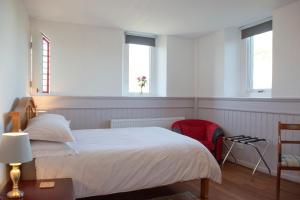a white bedroom with a bed and two windows at Old Church in Inverness